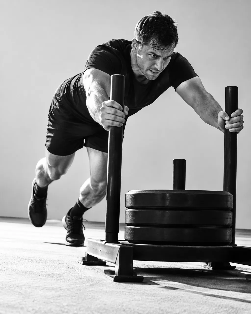 Man pushing a weighted sled across a training floor